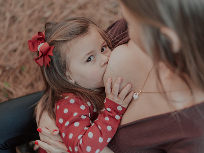 Foto de uma mãe amamentando sua filha de 2 anos.
