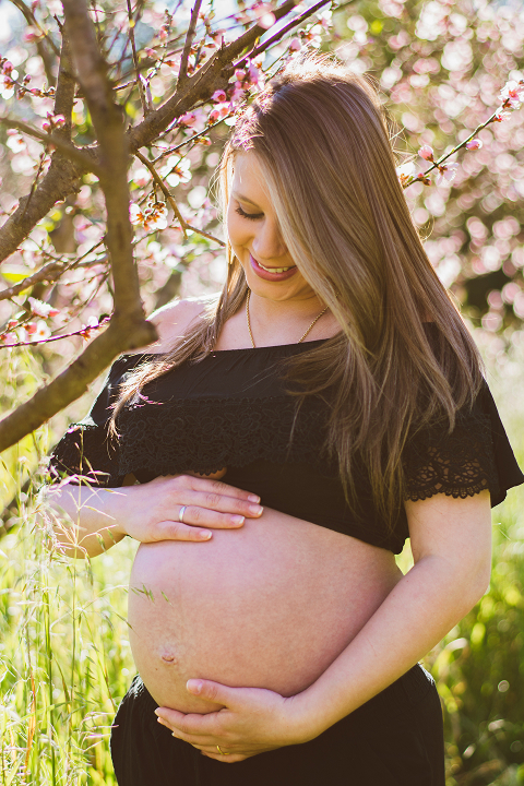 Foto de uma gestante sorrindo, com as mãos sobre a barriga.